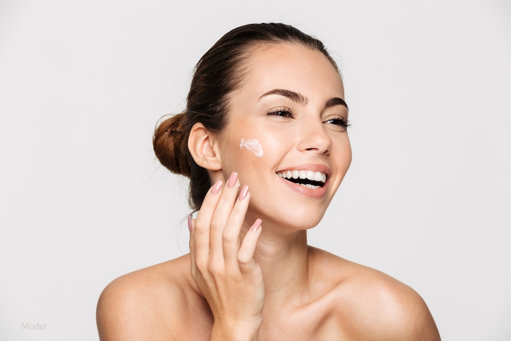 Happy woman applying skincare properly to maintain good skin health.