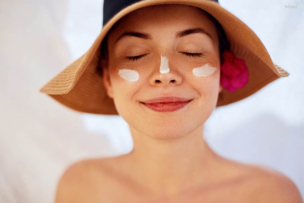 Happy woman wearing sunscreen and hat to protect her skin from the sun.